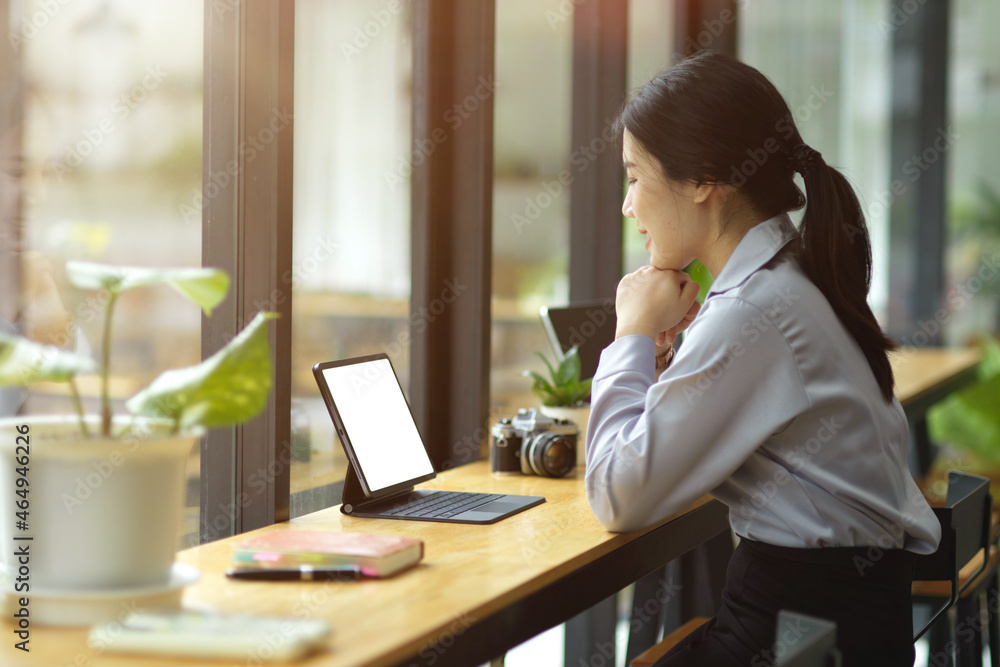 Obraz premium Beautiful young asian businesswoman working on tablet, looking on screen