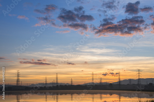 Lined high voltage poles and reflections in the beautiful morning water and lake view, Mae Moh, Lampang, Thailand