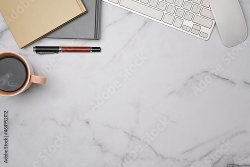 Top view woman workspace with cup of coffee, notebooks and keyboard on marble table. photo