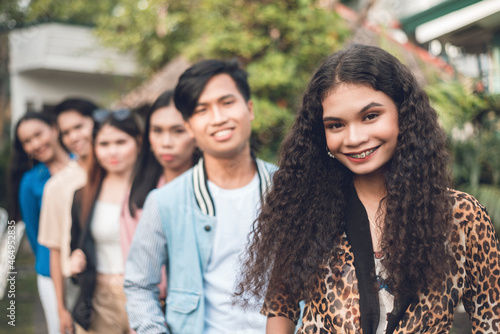 A group of six young and dynamic friends from late teens to early 20s, in a single file. Outdoor scene. photo