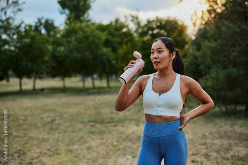 Sporty young woman drinking water after outdoors workout