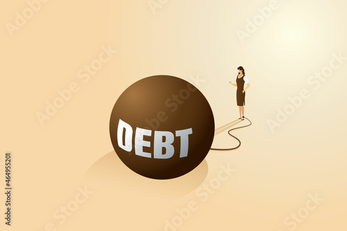 Businesswoman is tethered to a large metal ball.