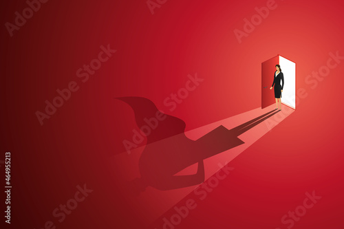 Businesswoman standing in front of an open door with a superhero reflection on the floor.