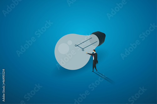 Businessman standing in front of a light bulb that goes out.