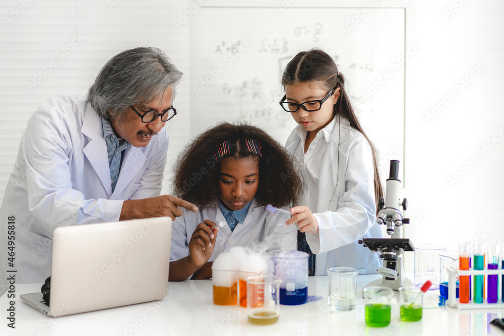Group of teenage students learning with teacher and doing a chemical experiment and holding test tube in hands in the experiment laboratory class on table at school.Education concept Group of teenage students learning with teacher and doing a chemical experiment and holding test tube in hands in the experiment laboratory class on table at school.Education concept