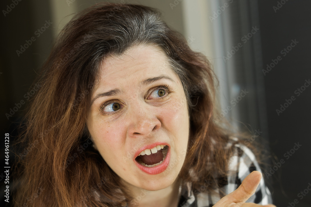 Horrified young woman looking in the bathroom mirror staring open mouthed at the first grey hair on her scalp, a first sign of ageing, or noticing that she is suffering from dandruff. Horrified young woman looking in the bathroom mirror staring open mouthed at the first grey hair on her scalp, a first sign of ageing, or noticing that she is suffering from dandruff.