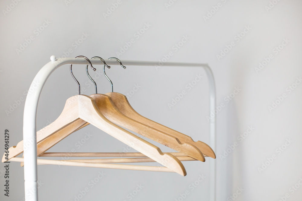 A wooden hanger hangs on a stainless steel rail in a room with white walls