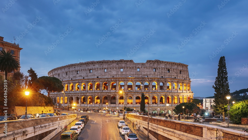 Rome, Italy. Colosseum. Traffic Near Flavian Amphitheatre During Sunset, Evening And Night Time. Famous World Landmark UNESCO. Day To Night Time Lapse