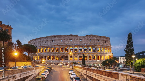 Rome, Italy. Colosseum. Traffic Near Flavian Amphitheatre During Sunset, Evening And Night Time. Famous World Landmark UNESCO. Day To Night Time Lapse