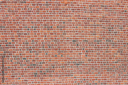 A wide brick blank wall of an old building. Uneven brickwork on a large wall.
