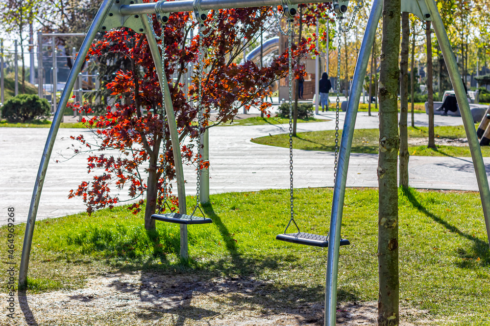 Fototapeta premium Children's swing in a public park. Outdoor playground.