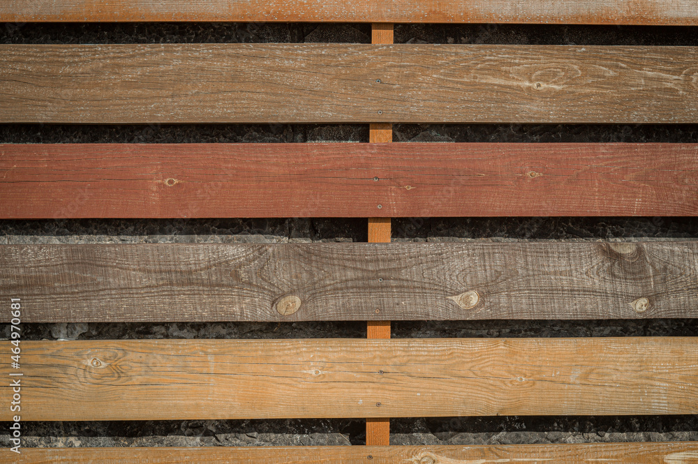 Wooden hedge on top of a concrete fence. Fence of colored boards. Background. Wooden hedge on top of a concrete fence. Fence of colored boards. Background.