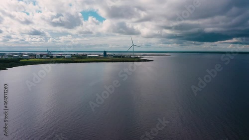 Aerial view of a wind power generator, at the sea, near a industrial area - circling, drone shot photo