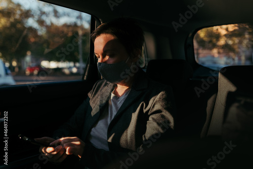 Businesswoman typing text message in car while wearing protective face mask for Covid-19 pandemic © Bits and Splits