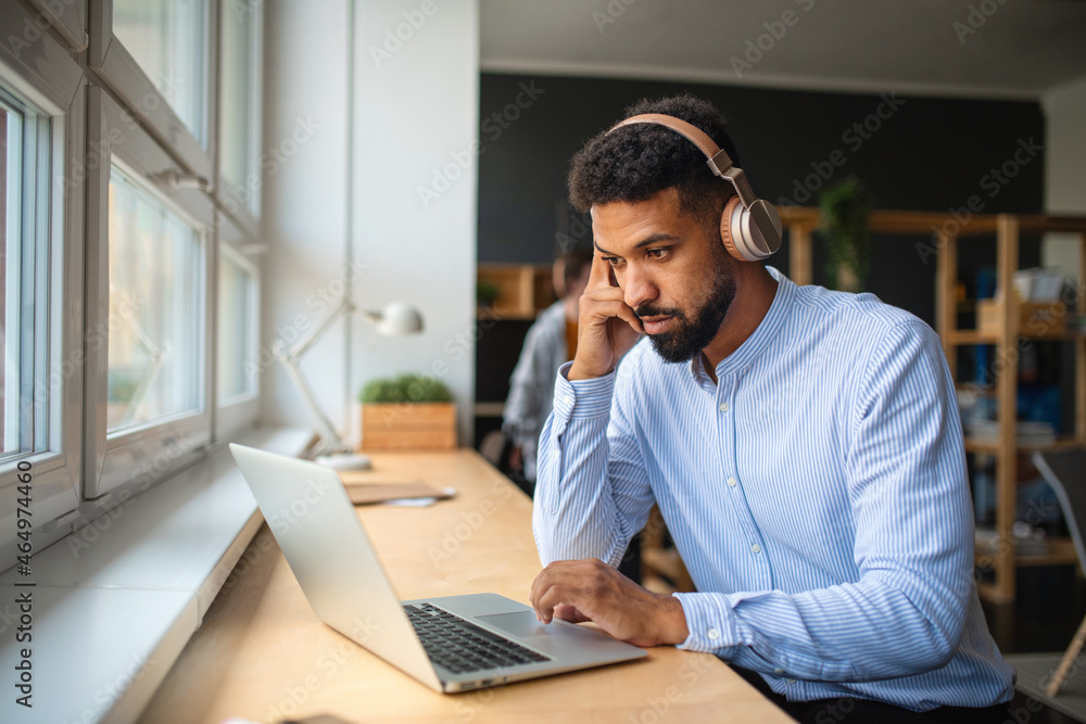 Young African-american teacher with headset and laptop indoors in staffroom. Young African-american teacher with headset and laptop indoors in staffroom.