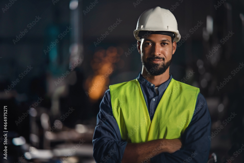 Portrait of happy young industrial man with protective wear indoors in metal workshop, looking at camera. - obrazy, fototapety, plakaty 