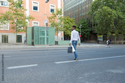 young black man shopping with paper bags crossing the street
