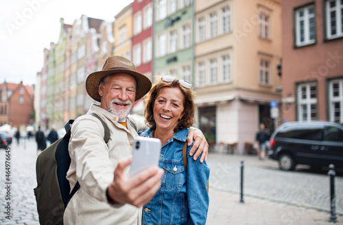 Portrait of happy senior couple tourists doing selfie outdoors in historic town