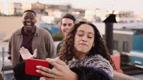 Multi-cultural female calling her friends to take a selfie on a rooftop in the city at dusk photo