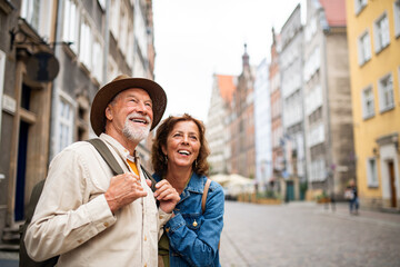 Portrait of happy senior couple tourists outdoors in historic town