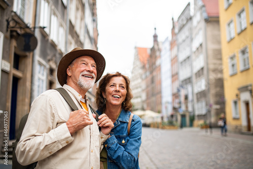 Portrait of happy senior couple tourists outdoors in historic town photo