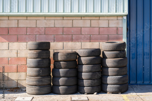 Four rows of used car wheels next to the workshop wall