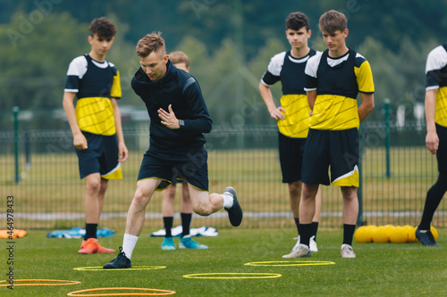 Young Football Coach on Training Session With Junior Footballers. Athletes Exercising With a Coach. Personal Trainer in Soccer Club Showing to Youth Players Training Drills