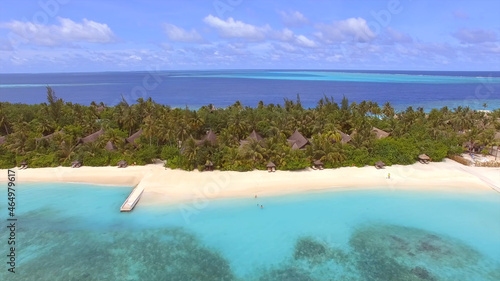Beautiful resort island in the Maldives  bungalows among palm trees  sandy beach  blue clear water