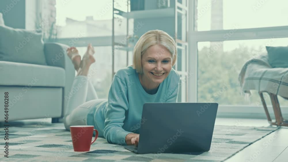 Cheerful relaxed smart lady lay floor typing distance work email