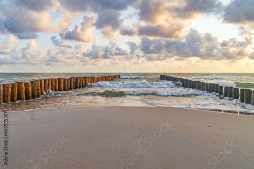 Sunrise on the Baltic sea, waves washing the old wooden breakwaters.