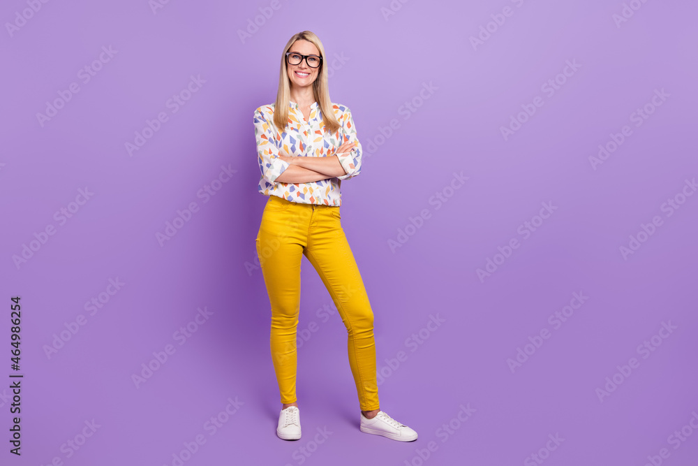 Photo of sweet charming young woman wear print shirt spectacles smiling arms crossed empty space isolated violet color background Photo of sweet charming young woman wear print shirt spectacles smiling arms crossed empty space isolated violet color background