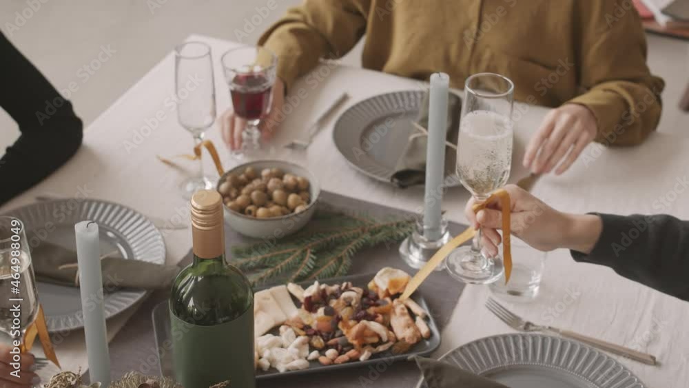 Top view of cropped friends with hands only in frame, pouring sparkling wine and clinking glasses on Christmas Top view of cropped friends with hands only in frame, pouring sparkling wine and clinking glasses on Christmas