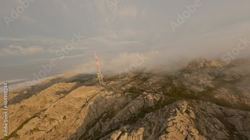 FPV video, mountain surfing, flying at high speed in the clouds with a granitic mountain range and an antenna farm during a beautiful sunrise. Mount Limbara (Monte Limbara) Tempio Pausania, Sardinia,  photo