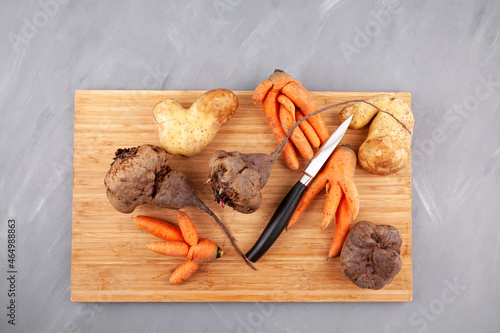 Different ugly vegetables on cutting board, top view. Concept - Food organic waste reduction. Using in cooking imperfect products photo