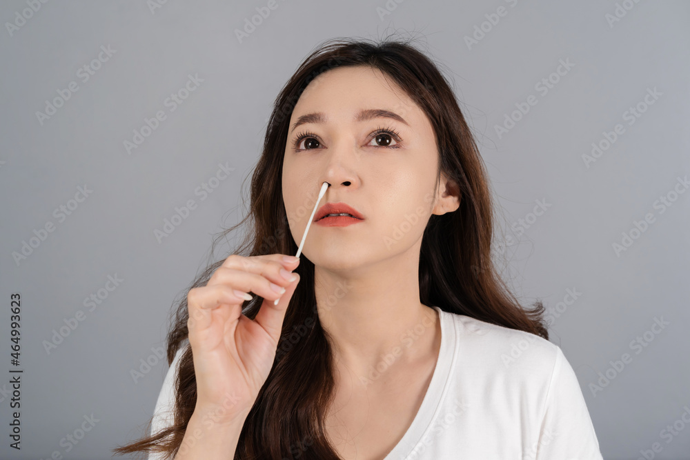 woman using coronavirus(covid-19) rapid antigen self test kit (atk) at home with cotton nasal swab woman using coronavirus(covid-19) rapid antigen self test kit (atk) at home with cotton nasal swab