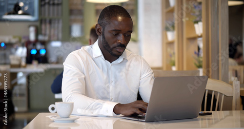 Portrait of mixed-race businessman working at laptop in restaurant