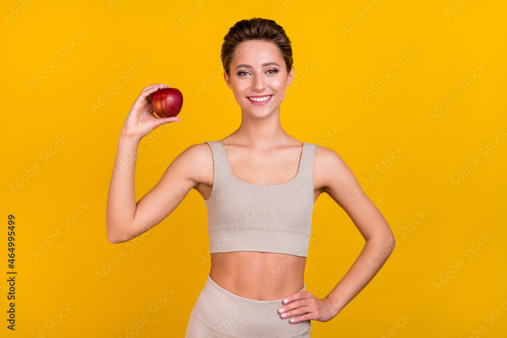 Portrait of attractive sportive cheerful girl holding on apple useful diet menu lunch isolated over bright yellow color background Portrait of attractive sportive cheerful girl holding on apple useful diet menu lunch isolated over bright yellow color background