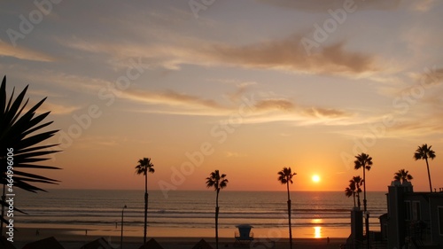 Palms silhouette sunset sky, California aesthetic. Oceanside USA. Tropical pacific ocean beach atmosphere. Dark black palm tree, Los Angeles vibes. Lifeguard watchtower, baywatch watch tower hut.