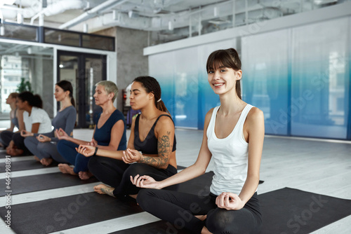 Smiling Caucasian woman practice yoga meditate at group class