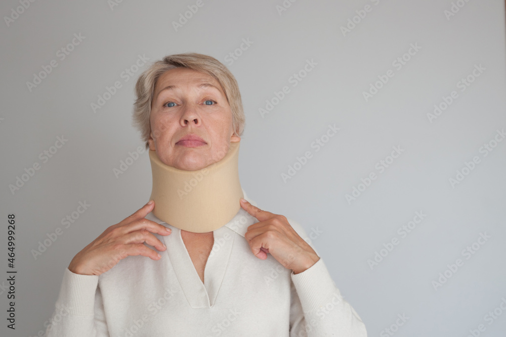 Portrait of an adult woman in a white jumper and a neck collar against a gray wall. Portrait of an adult woman in a white jumper and a neck collar against a gray wall.