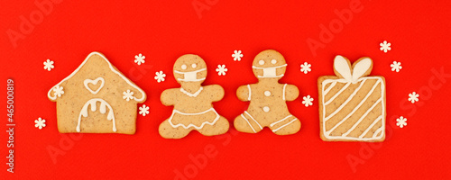 Happy New Year's 2022 set of gingerbread man in face mask from ginger biscuits glazed sugar icing decoration on classic traditional red background, minimal seasonal pandemic winter holiday banner photo