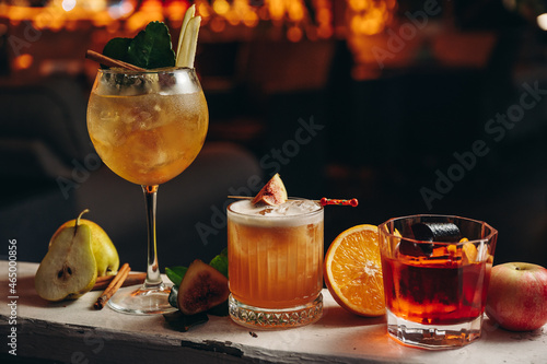 Three different beautiful cocktails in warm colors on a flower background