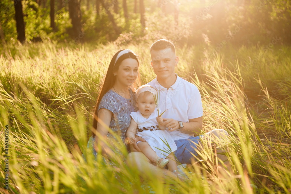 Fototapeta premium Happy family dad, mom playing in the fresh air on the field watching the beautiful emotional sunset in the backlight