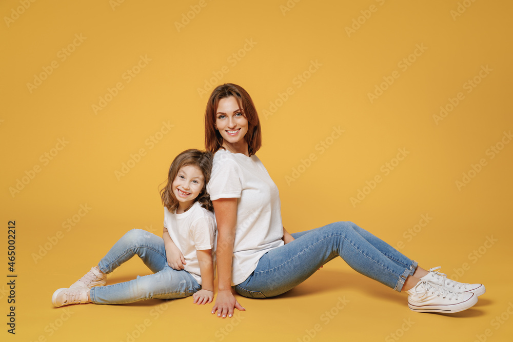 Full body length happy woman in basic white t-shirt have fun sit on floor child baby girl 5-6 years old Mom mum little kid daughter isolated on yellow color background studio Mother's Day love family. Full body length happy woman in basic white t-shirt have fun sit on floor child baby girl 5-6 years old Mom mum little kid daughter isolated on yellow color background studio Mother's Day love family.