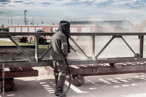 Foto A worker in a special suit is sandblasting metal at an industrial site