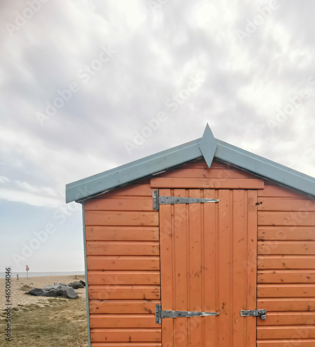 Brown beach hut or shed beside beach on grey cloudy day