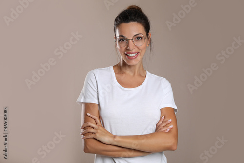 Beautiful woman in eyeglasses on light brown background