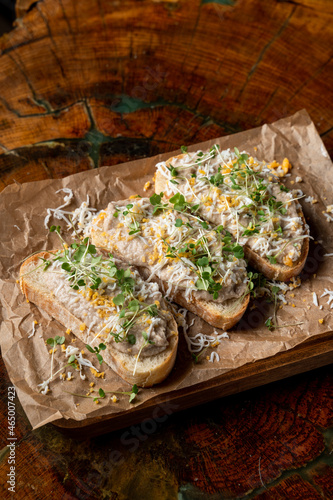 Two forshmak sandwiches on a wooden tray, darks lights soft shadows