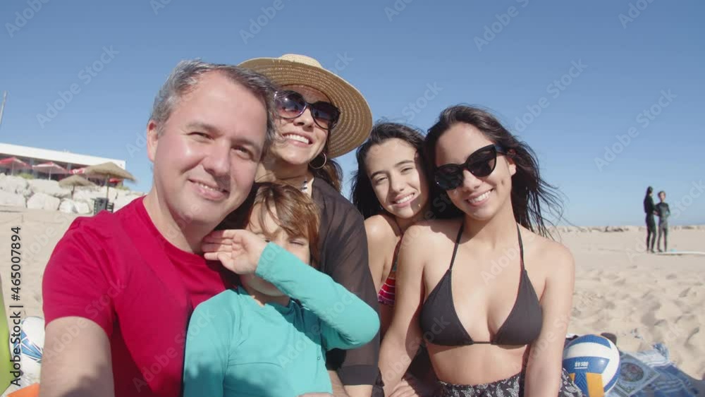 POV of father taking selfie with happy family on sandy beach. Front view of big Caucasian family sitting together taking photo during summer vacation at sea, looking at camera. Photoshoot concept POV of father taking selfie with happy family on sandy beach. Front view of big Caucasian family sitting together taking photo during summer vacation at sea, looking at camera. Photoshoot concept
