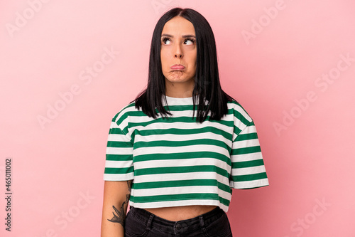 Young caucasian woman with one arm isolated on pink background confused, feels doubtful and unsure.